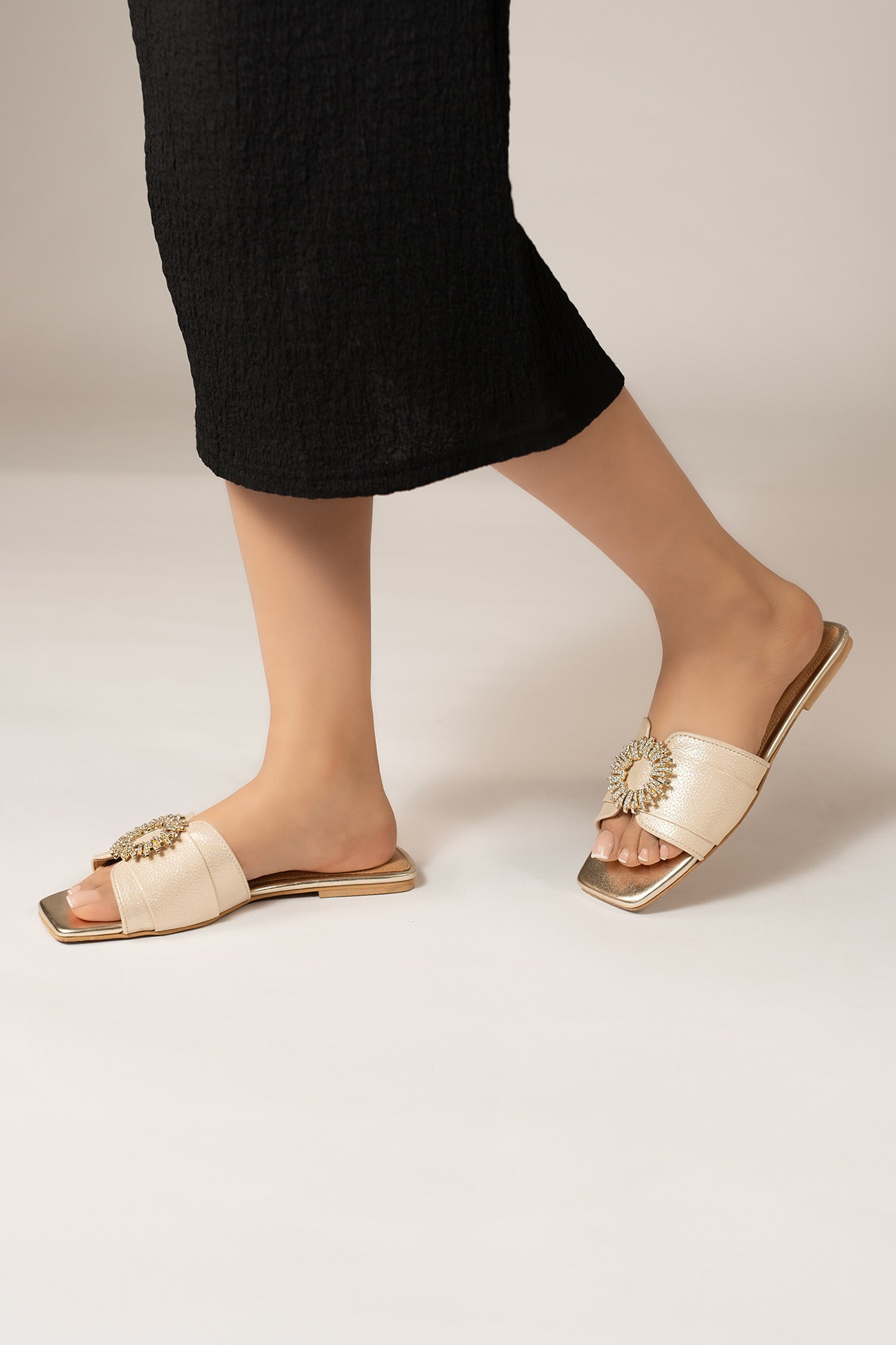 Women's festive leatherite flat shoes in light gold colour with glitter strap and round golden diamante brooch by JULKE.