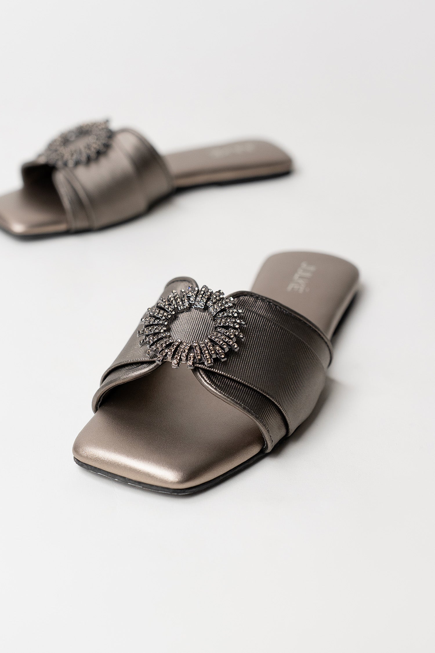 Women's festive leatherite flat shoes in gun metal colour with round silver diamante brooch and padded insock by JULKE.
