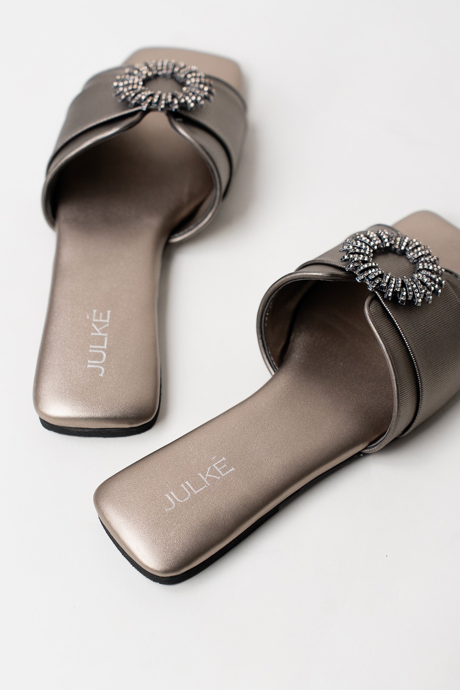 Women's festive leatherite flat shoes in gun metal colour with round silver diamante brooch and padded insock by JULKE.