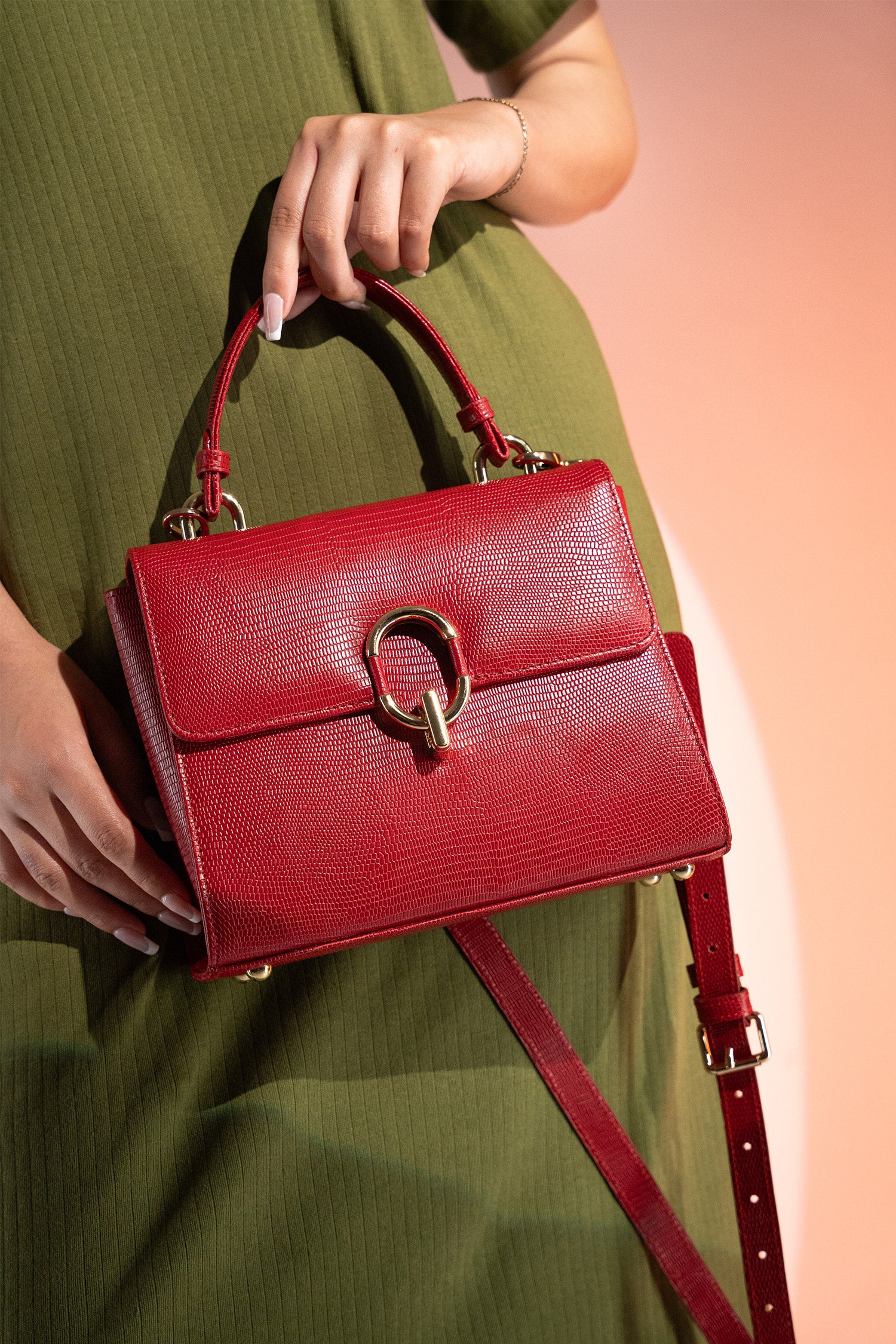 Women's reptile texture leather top handle bag in red colour with detachable shoulder strap and unique oval twist lock by JULKE.