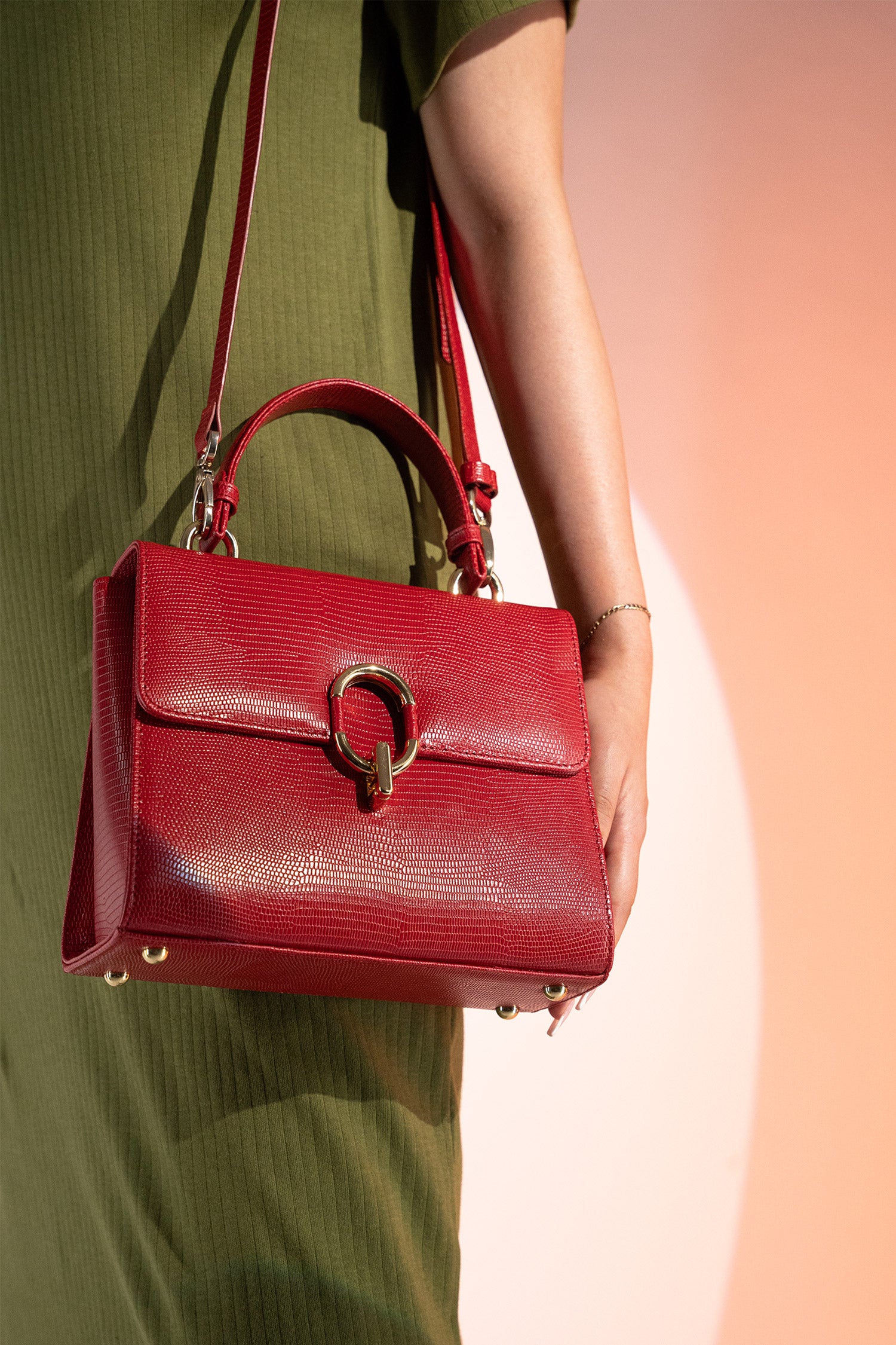 Women's reptile texture leather top handle bag in red colour with detachable shoulder strap and unique oval twist lock by JULKE.