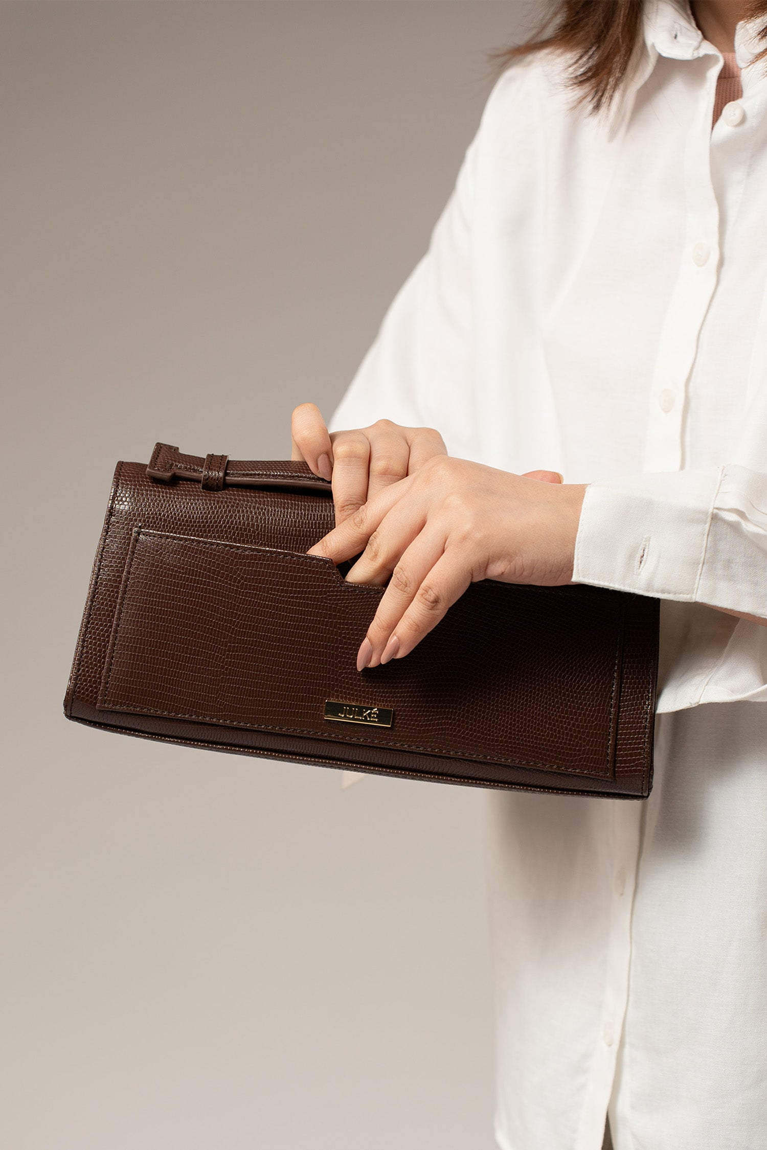 Womens leather top handle shoulder bag in dark brown colour with reptile texture and oval gold buckle by JULKE.