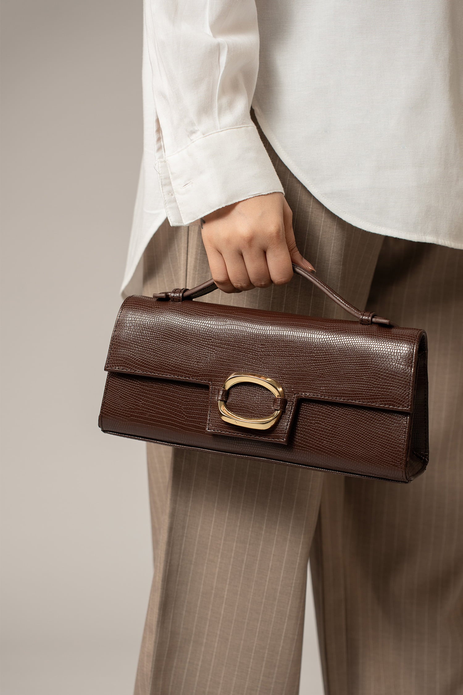Womens leather top handle shoulder bag in dark brown colour with reptile texture and oval gold buckle by JULKE.