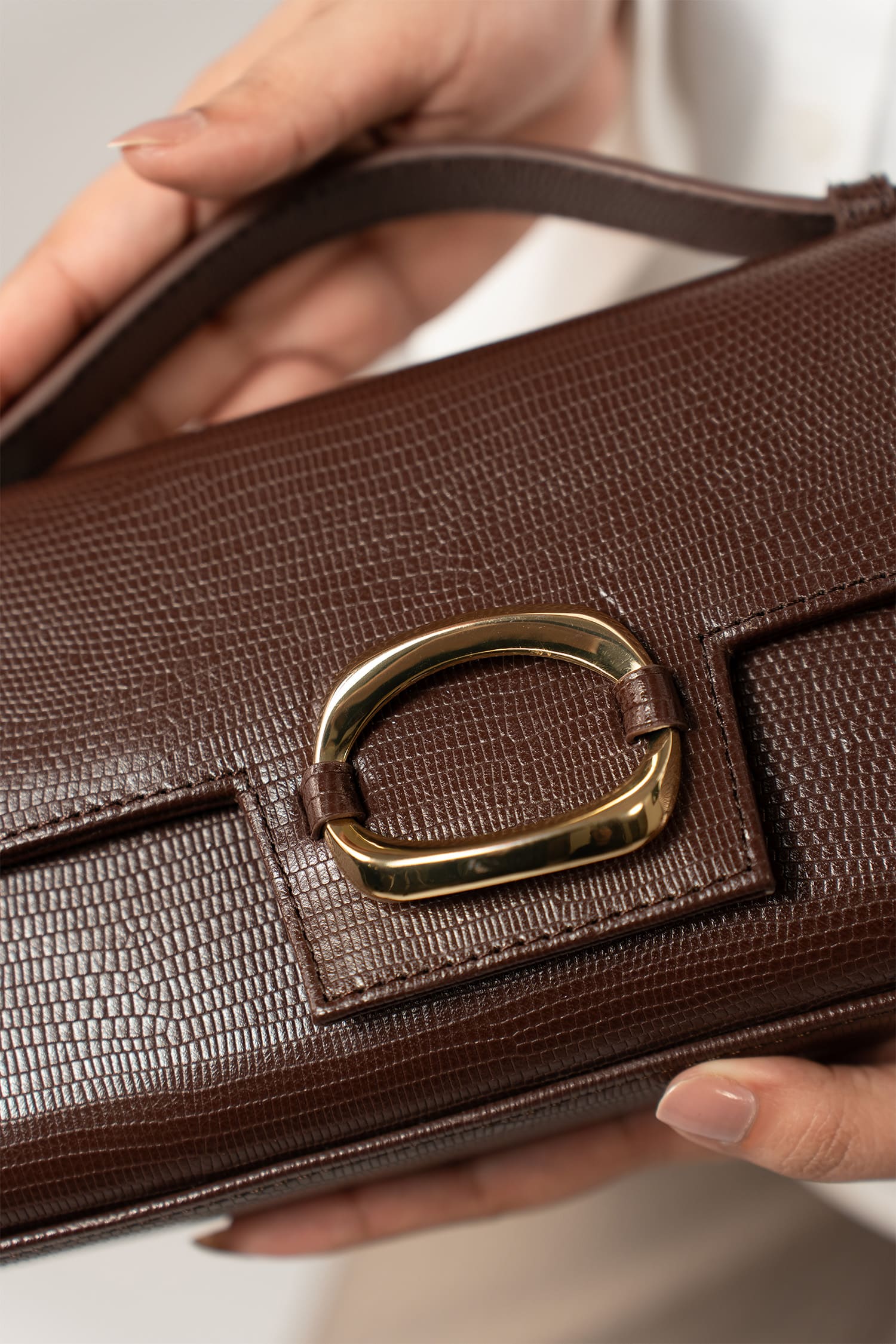 Womens leather top handle shoulder bag in dark brown colour with reptile texture and oval gold buckle by JULKE.