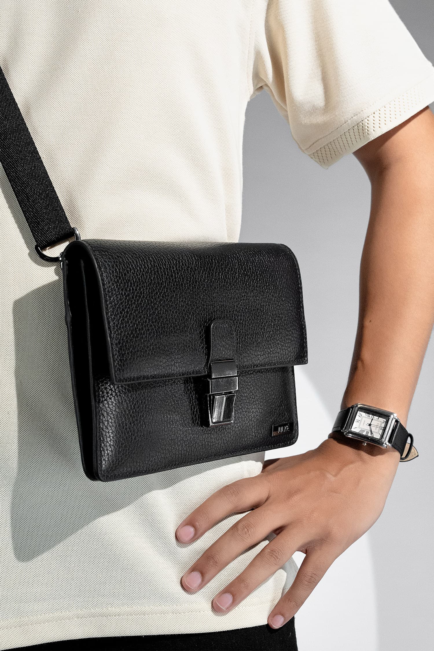 Unisex soft leather small travel crossbody bag in black colour with metal push lock spacious pockets and detachable wide strap by JULKE