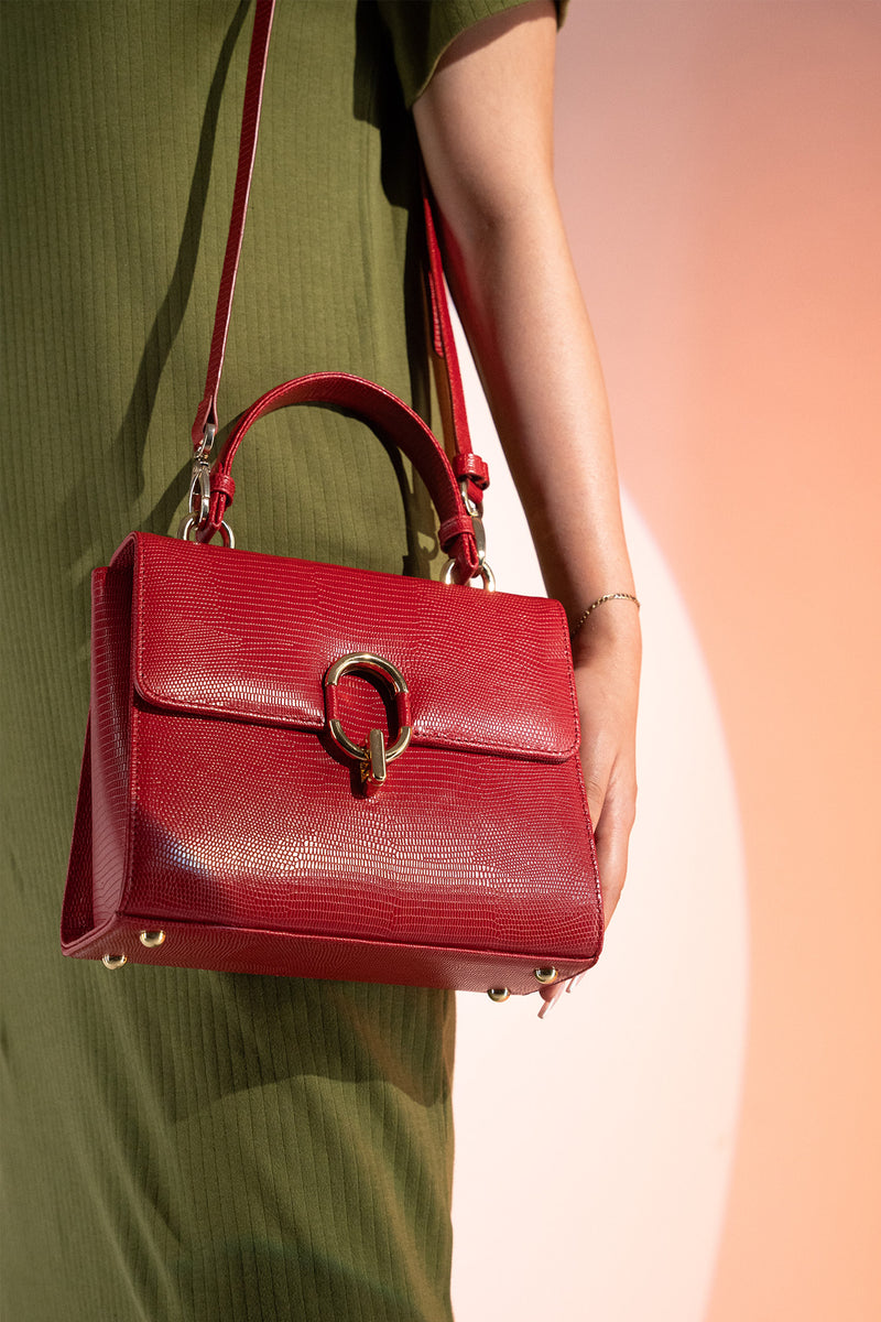 Women's reptile texture leather top handle bag in red colour with detachable shoulder strap and unique oval twist lock by JULKE. 