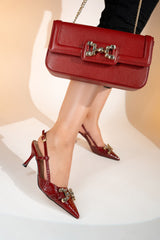 Women's sling back pointed toe heels in dark red colour and matching leather shoulder bag with glossy dragon scale texture and rhinestone horse-bit buckle by JULKE. 