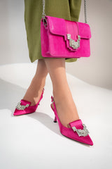 Women's sling back pointed toe heels in hot pink colour satin with geometric white rhinestone brooch and matching clutch bag by JULKE