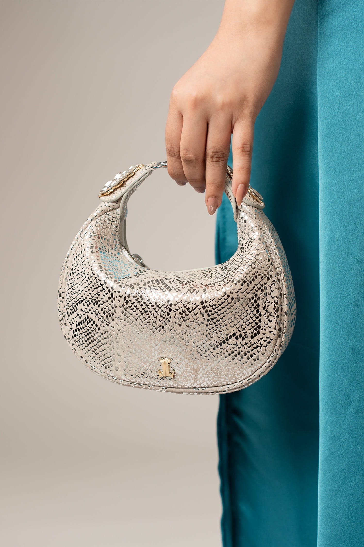 Women's leather mini halfmoon bag in silver colour with 3d reptile texture and unique clip-on handle by JULKE.