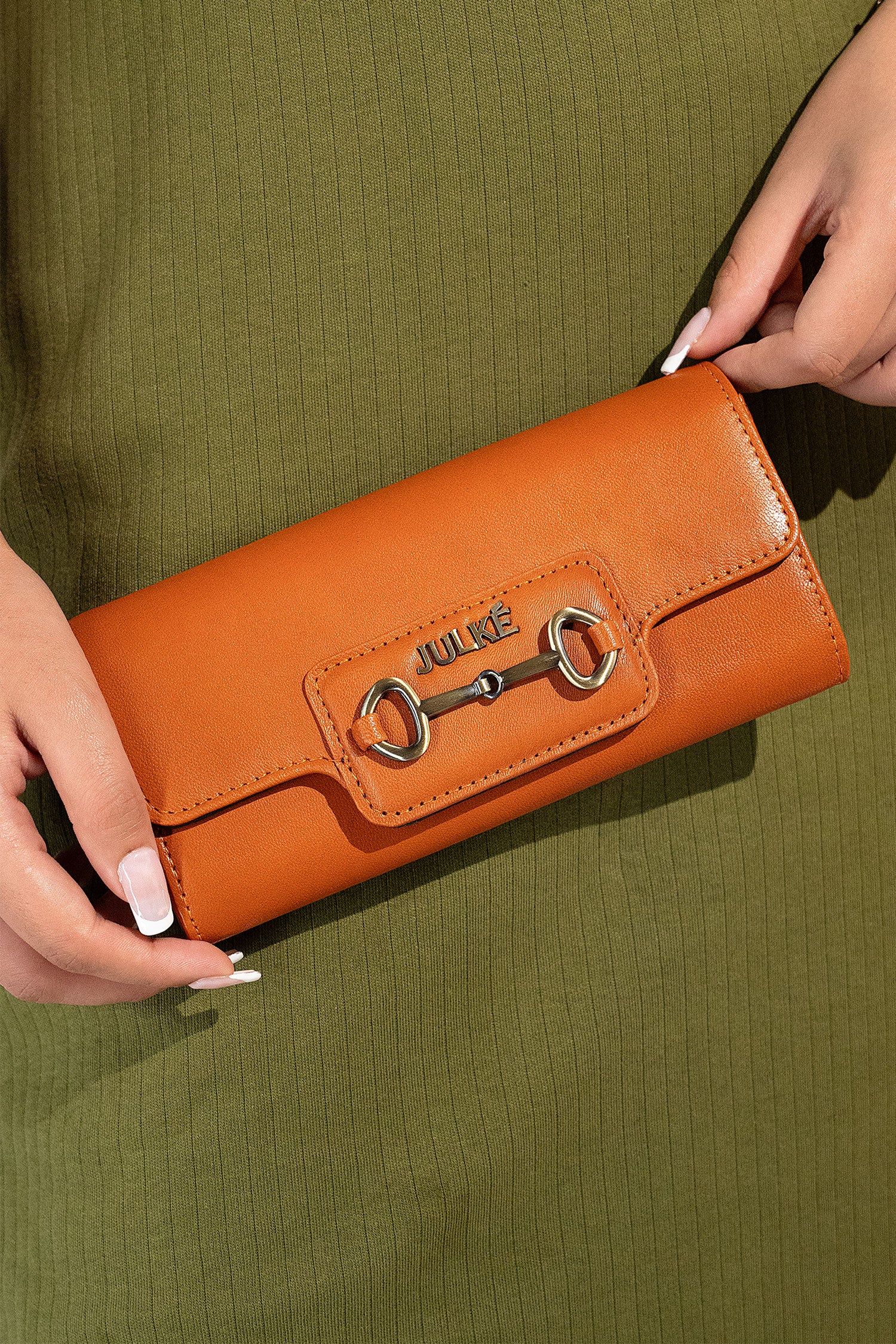 Women's leather long wallet in dark orange colour in envelope shape with long pockets and metallic horse-bit buckle and brand logo by JULKE. 