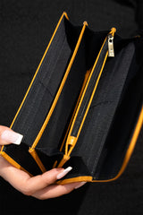 Women's leather long wallet in mustard yellow colour in envelope shape with long pockets and metallic horse-bit buckle and brand logo by JULKE. 
