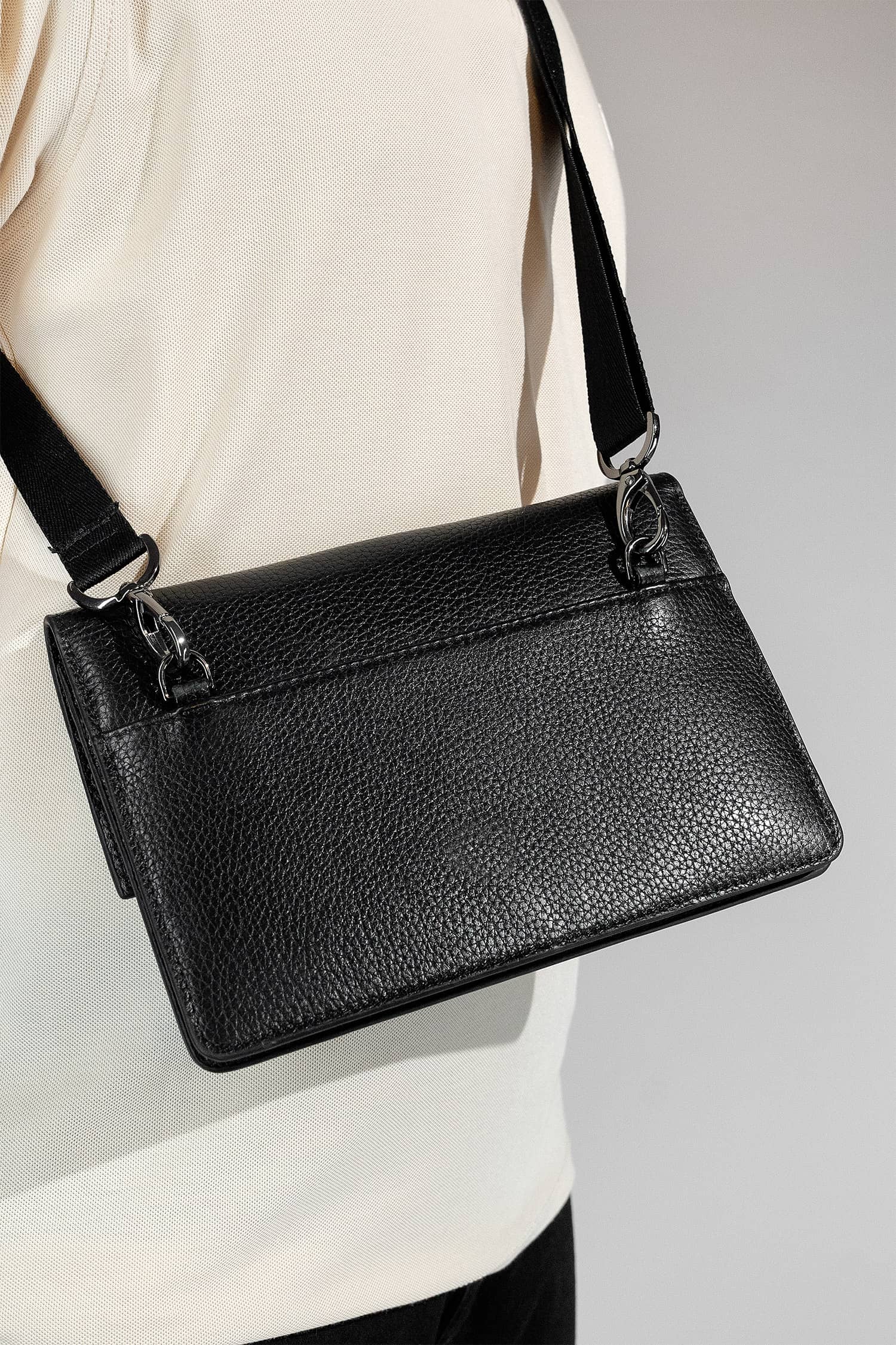 Unisex soft leather small travel crossbody bag in black colour with metal push lock spacious pockets and detachable wide strap by JULKE